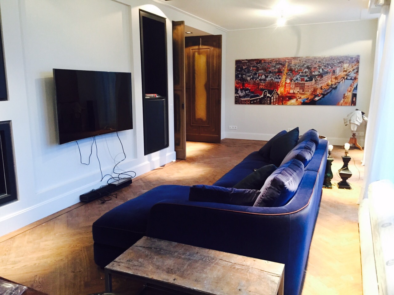 Zitkamer van het penthouse met ingebouwde tv-wand, haard en houten vloer